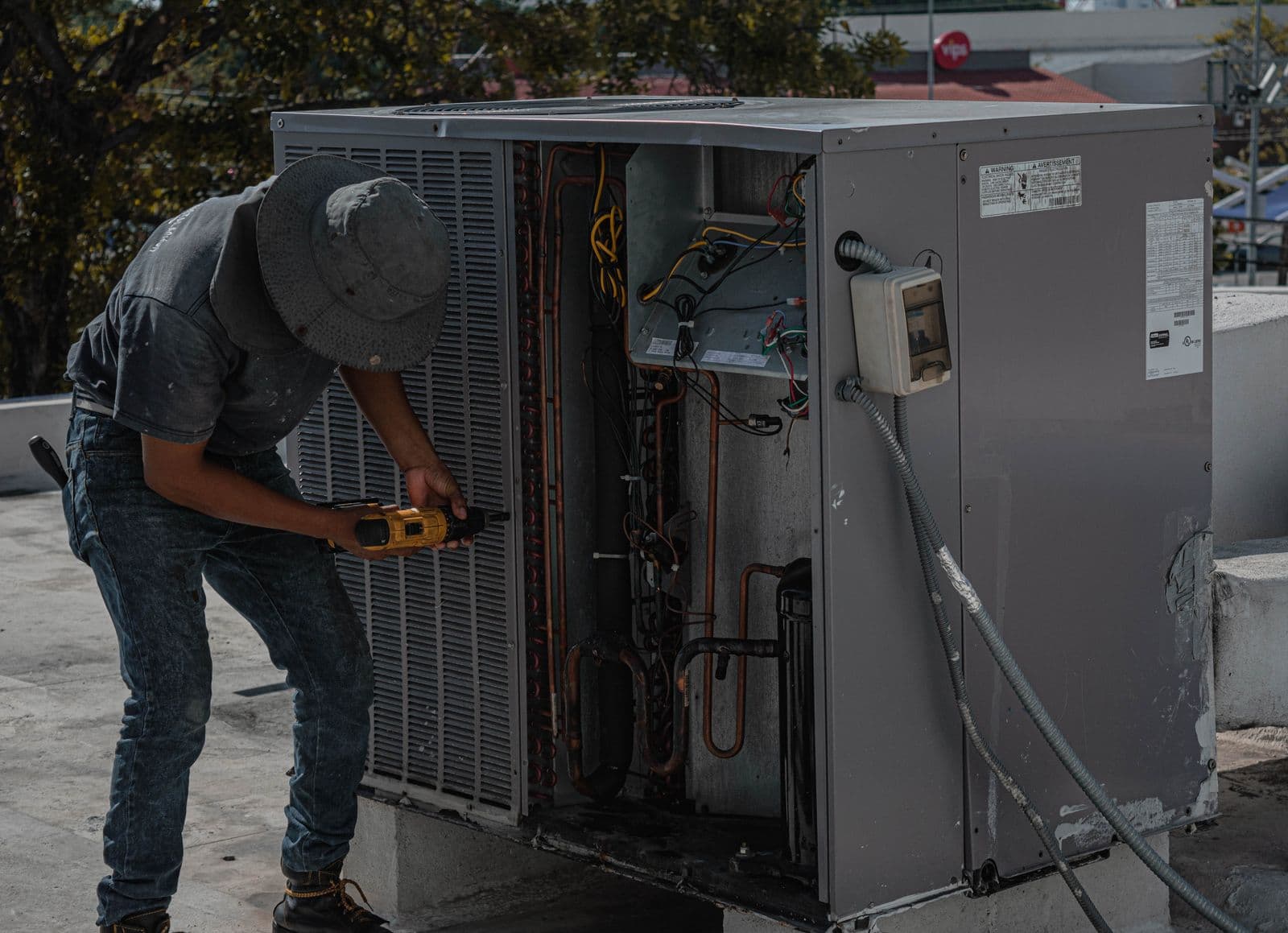 Técnico con atornillador eléctrico interviniendo una unidad de aire acondicionado con los paneles abiertos y el serpentín a la vista — Reparación de aires en Bucaramanga y Barranquilla